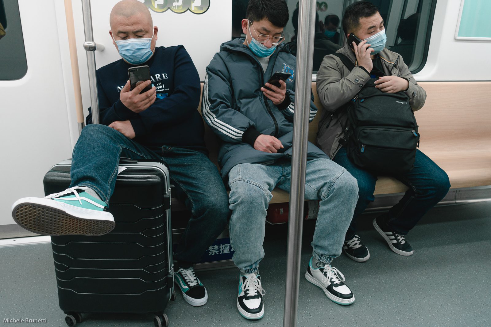 Michele Brunetti - three guys looking at their phone on the subway, between stops.